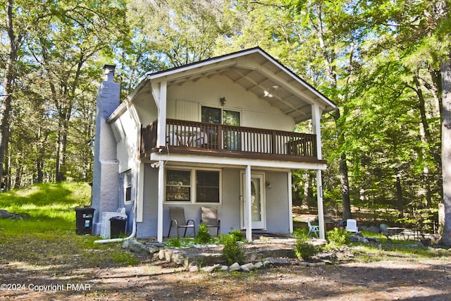 view of front of home featuring a chimney, a balcony, and central air condition unit