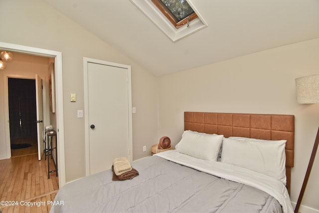 bedroom featuring vaulted ceiling with skylight and light wood-style flooring