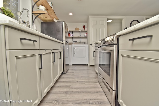 kitchen with light wood finished floors, stainless steel electric stove, recessed lighting, a sink, and independent washer and dryer