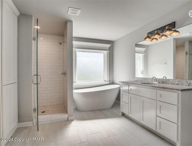 bathroom featuring a stall shower, visible vents, a freestanding bath, and vanity