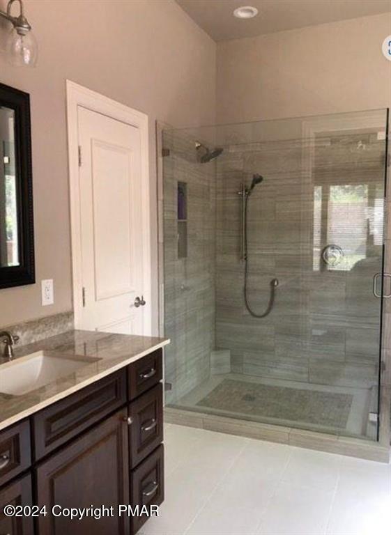 full bathroom featuring a stall shower, tile patterned flooring, and vanity