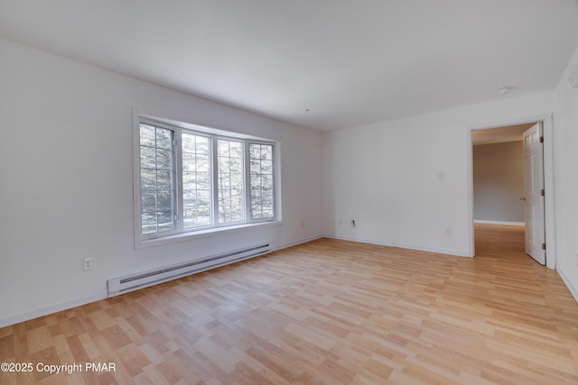 spare room featuring a baseboard heating unit and light wood-type flooring