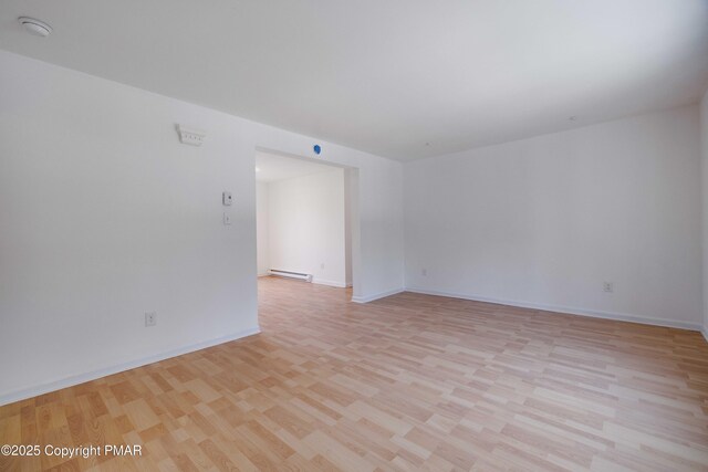 spare room with a baseboard heating unit and light hardwood / wood-style flooring