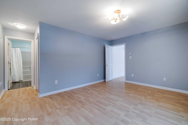 unfurnished bedroom featuring ensuite bath and light wood-type flooring