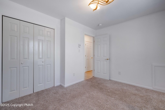 unfurnished bedroom featuring light colored carpet and a closet