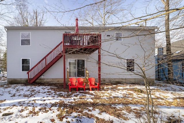 snow covered back of property with a wooden deck