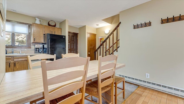 dining room with stairway, a baseboard radiator, and wood finished floors