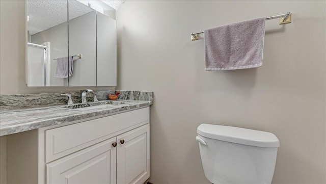 bathroom featuring a textured ceiling, vanity, and toilet