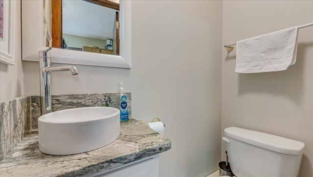 bathroom with toilet, a textured ceiling, and vanity