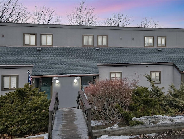 view of property with roof with shingles and stucco siding