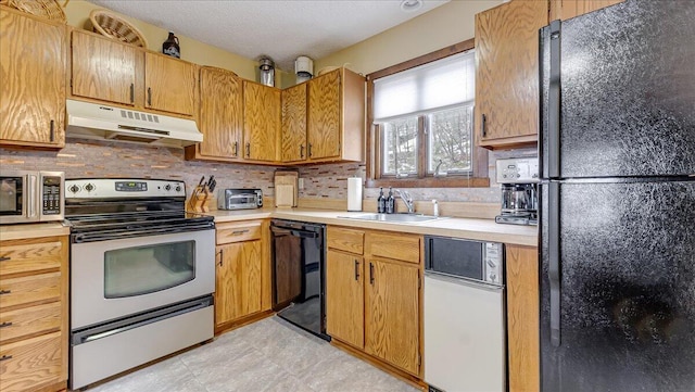 kitchen featuring tasteful backsplash, light countertops, a sink, under cabinet range hood, and black appliances