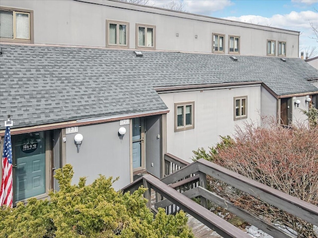 back of property with a shingled roof and stucco siding