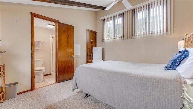 carpeted bedroom with beamed ceiling, ensuite bath, and baseboards