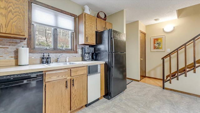 kitchen with a textured ceiling, a sink, light countertops, backsplash, and black appliances