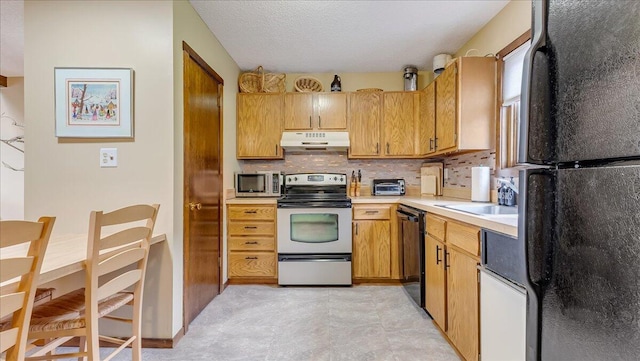 kitchen with decorative backsplash, under cabinet range hood, light countertops, black appliances, and a sink