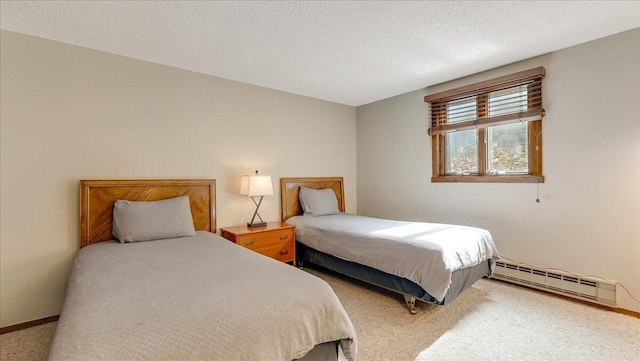 bedroom featuring a baseboard heating unit, light carpet, a textured ceiling, and baseboards