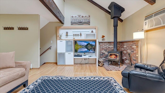 living room with a wood stove, a wall unit AC, lofted ceiling with beams, and wood finished floors