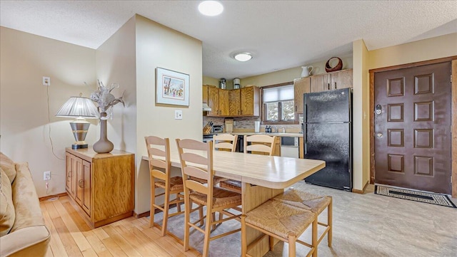 dining area with baseboards, a textured ceiling, and light wood finished floors