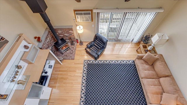 living area featuring a wood stove, a wall unit AC, and hardwood / wood-style floors