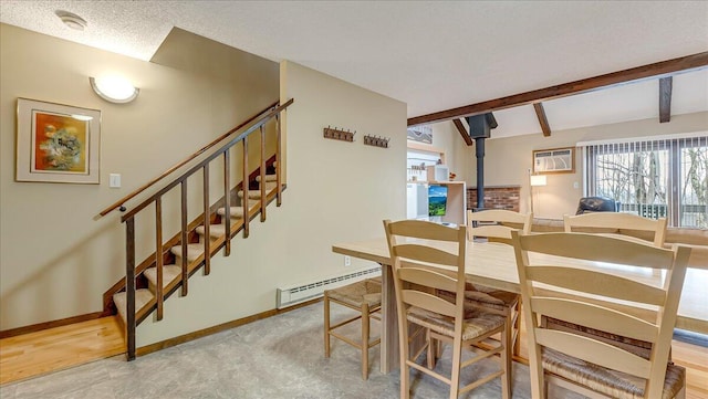 dining room featuring baseboards, a wood stove, baseboard heating, a textured ceiling, and an AC wall unit