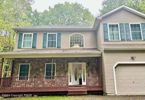 view of front of property with covered porch, stone siding, and a garage