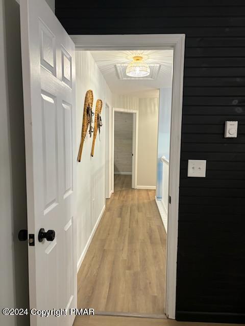 corridor featuring light wood-style flooring and baseboards