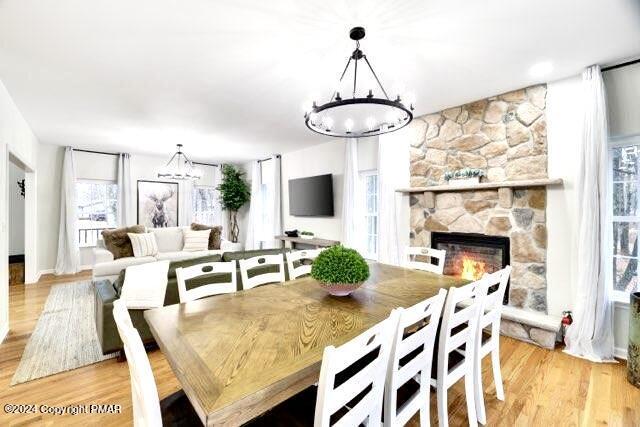 dining area featuring a fireplace, light wood finished floors, and an inviting chandelier