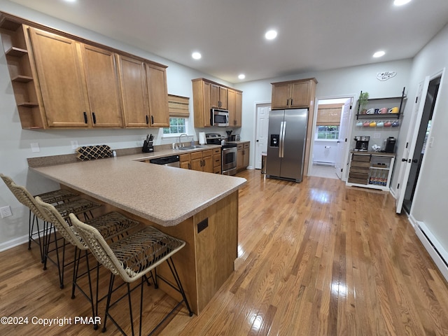 kitchen with stainless steel appliances, light wood-style floors, a peninsula, and open shelves