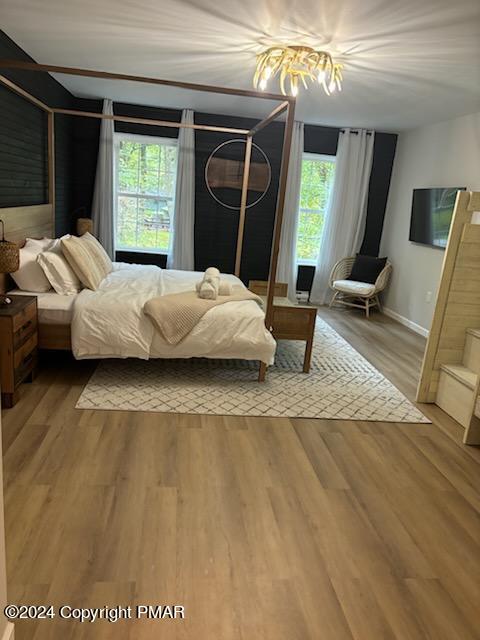 bedroom featuring baseboards, multiple windows, and light wood-style floors