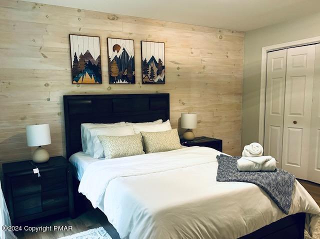 bedroom featuring a closet and wooden walls