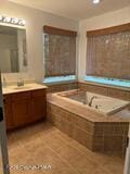 bathroom with a garden tub, vanity, and tile patterned floors