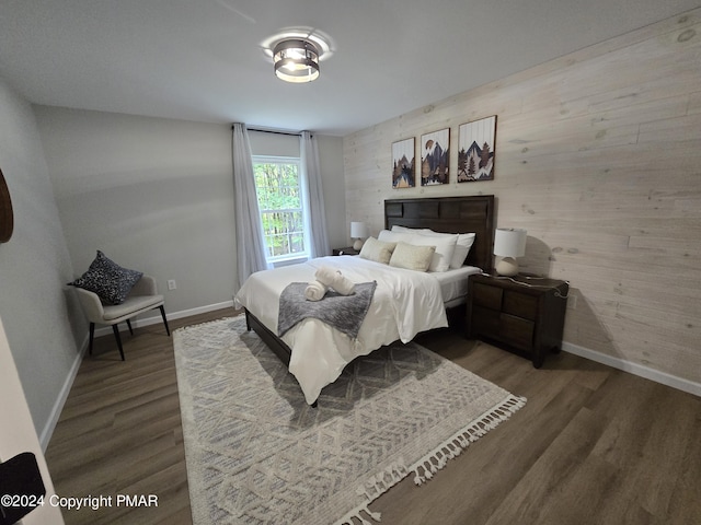 bedroom featuring wood walls, baseboards, and wood finished floors