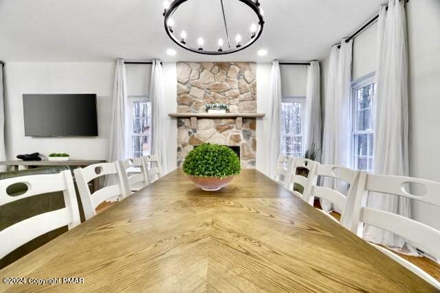 dining space with an inviting chandelier and a stone fireplace