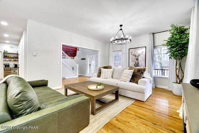 living room with light wood finished floors, recessed lighting, stairway, an inviting chandelier, and baseboards