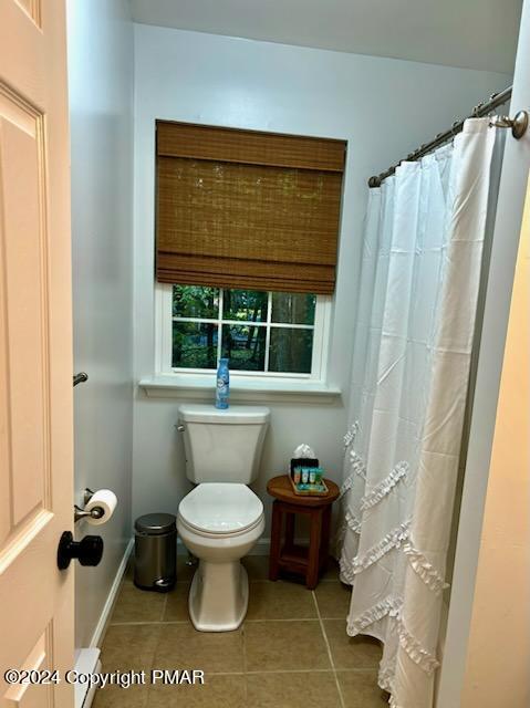 full bathroom featuring toilet, a shower with curtain, baseboards, and tile patterned floors