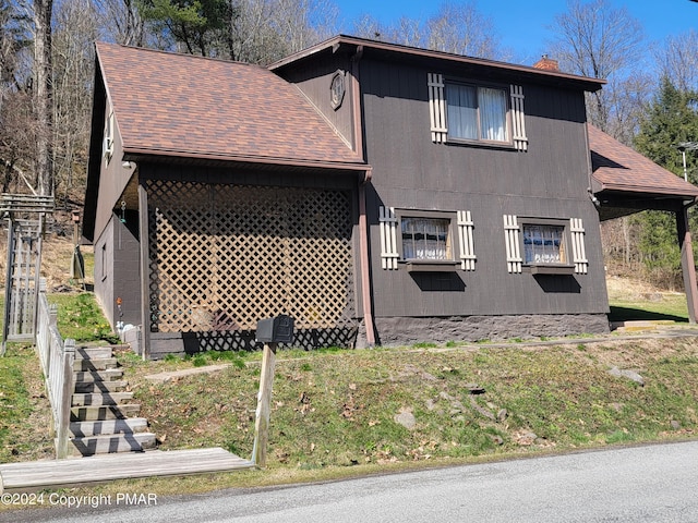 view of property exterior with a shingled roof and a chimney