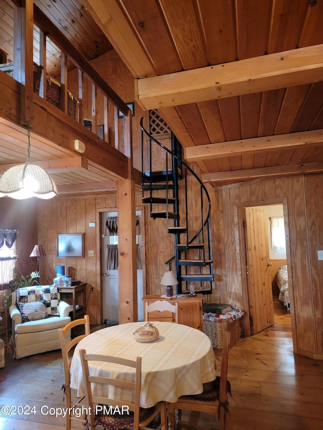 dining area with wood walls, stairs, wooden ceiling, hardwood / wood-style flooring, and beamed ceiling