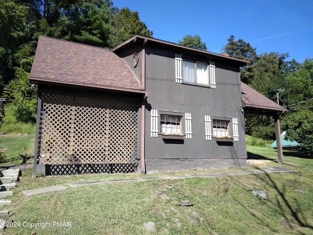 back of house featuring a yard and roof with shingles
