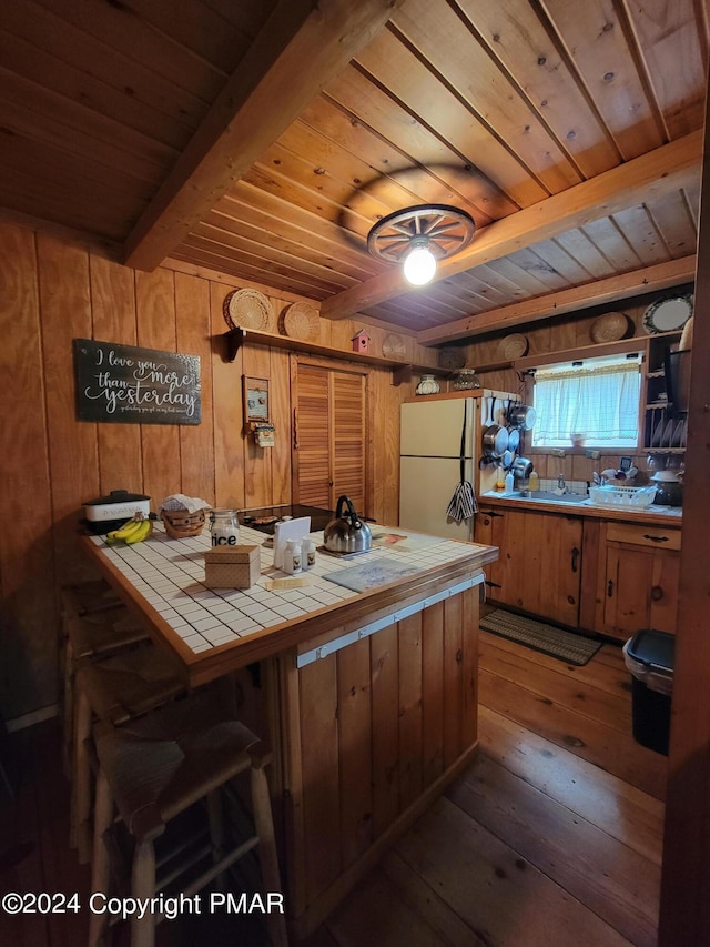kitchen with wooden ceiling, freestanding refrigerator, tile countertops, beamed ceiling, and hardwood / wood-style floors