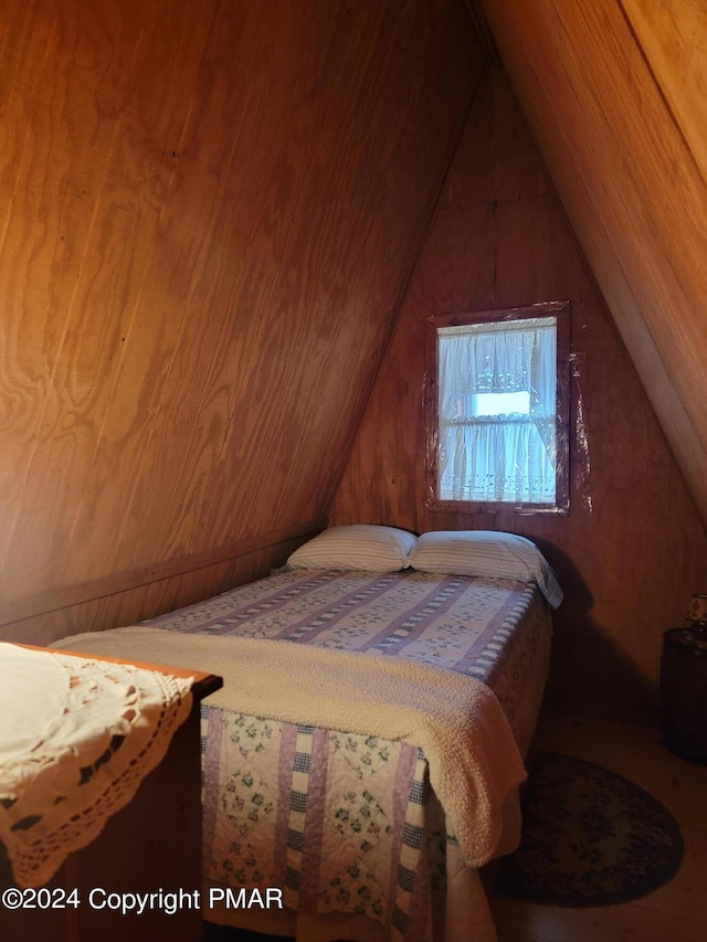 bedroom with lofted ceiling and wooden walls