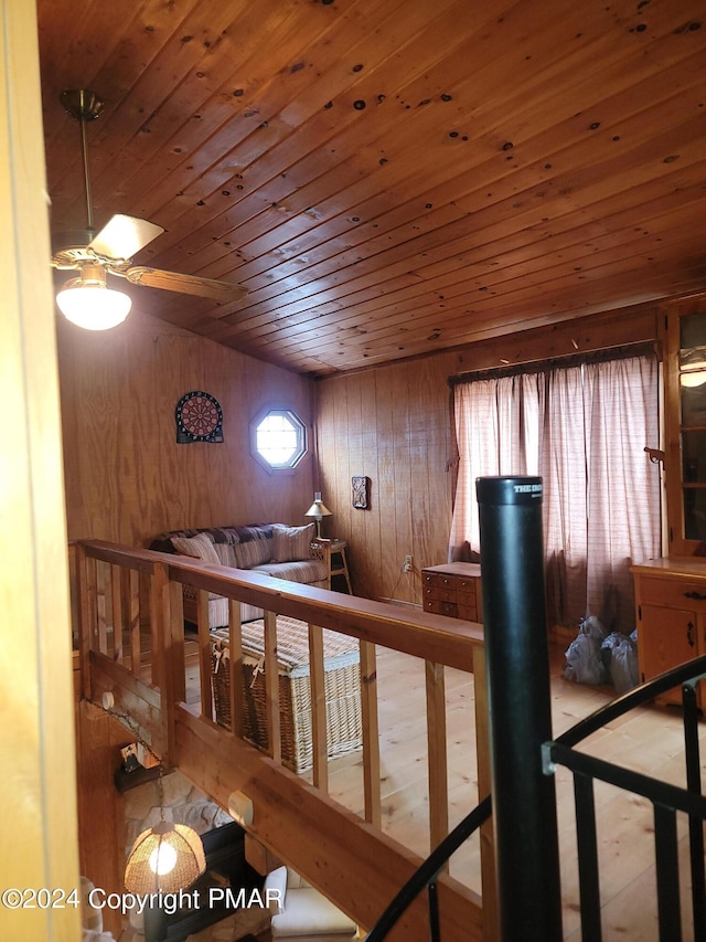 staircase featuring wooden ceiling, ceiling fan, and wood walls