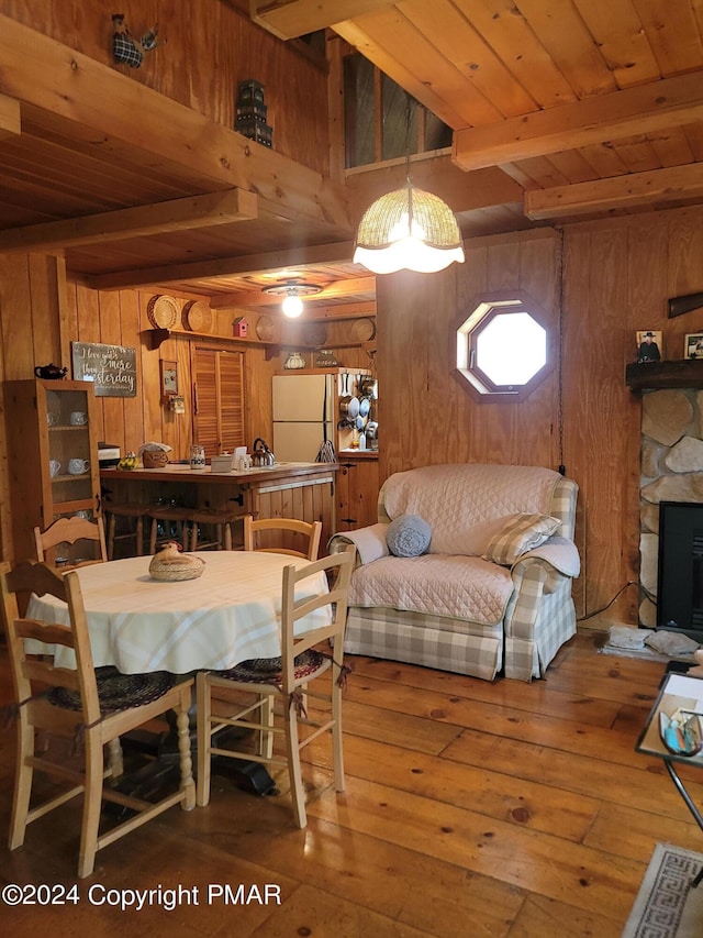 dining room featuring beamed ceiling, wood walls, and hardwood / wood-style flooring