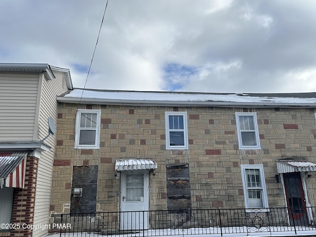 view of front of home with stone siding and fence