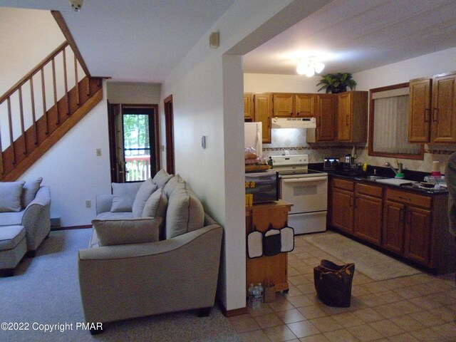 101 Withywindle Way, Tamiment, PA 18371 - kitchen featuring white range with electric stovetop, under cabinet range hood, open floor plan, backsplash, and brown cabinets