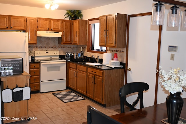 101 Withywindle Way, Tamiment, PA 18371 - kitchen featuring white appliances, under cabinet range hood, backsplash, dark countertops, and brown cabinetry