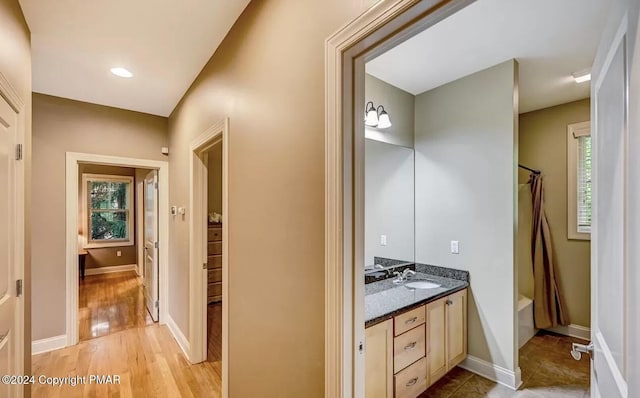 full bath with wood finished floors, shower / bath combo with shower curtain, vanity, and baseboards