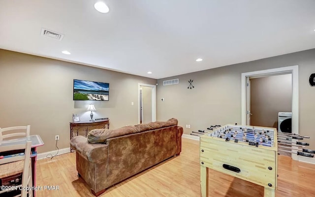 living area featuring light wood finished floors, baseboards, visible vents, and washer / clothes dryer