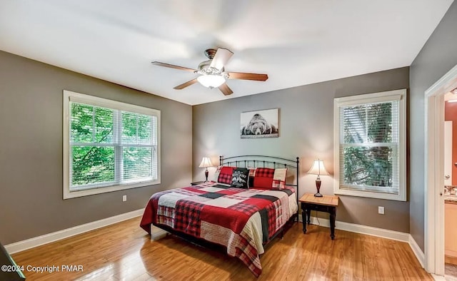 bedroom featuring a ceiling fan, connected bathroom, light wood finished floors, and baseboards