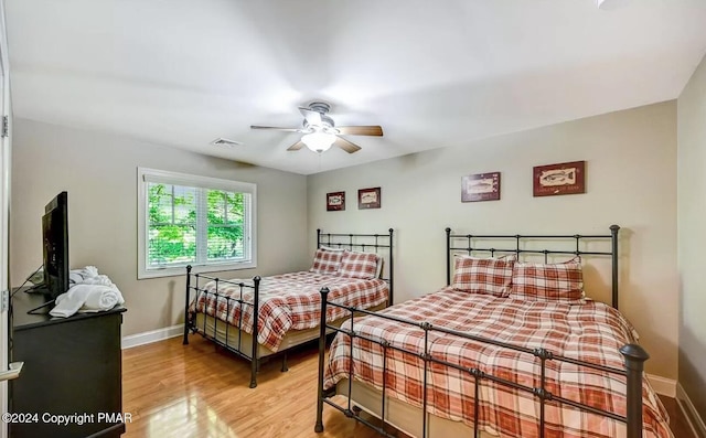 bedroom with a ceiling fan, light wood-type flooring, visible vents, and baseboards