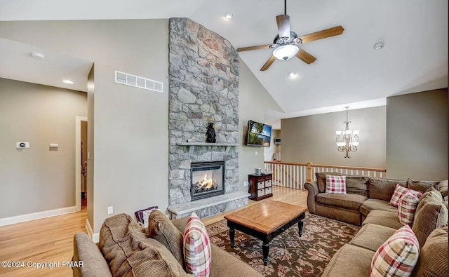 living area featuring high vaulted ceiling, a stone fireplace, wood finished floors, visible vents, and baseboards